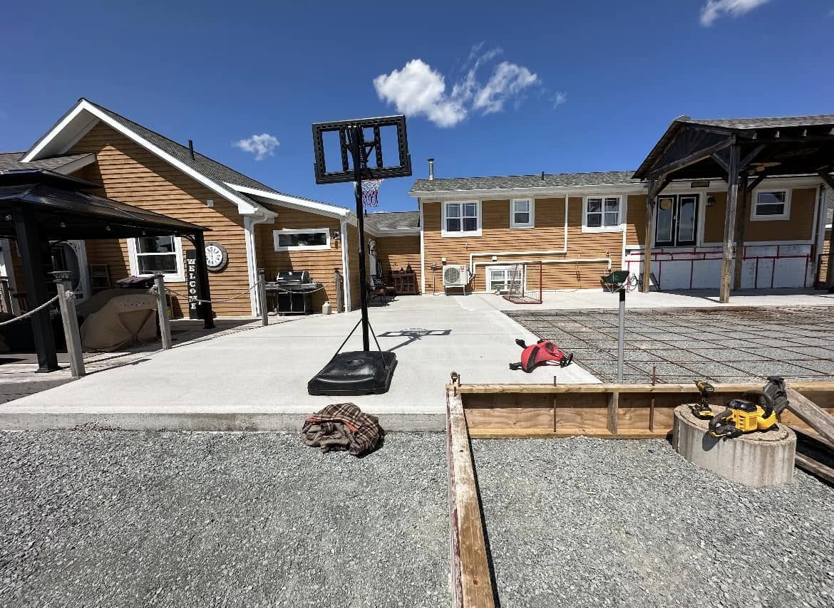 Finished concrete pad and covered timber structure behind a completed home